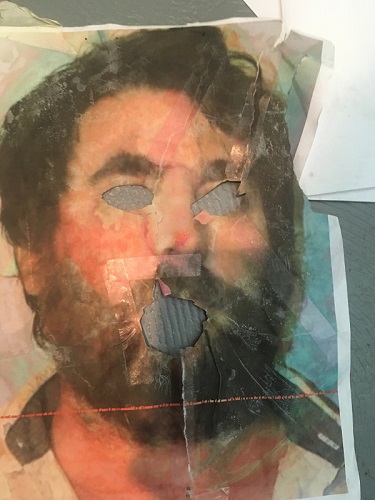 Image of picture of artist, Richard Haley's face with his eyes and mouth torn away revealing a light blue/grey fileld behind