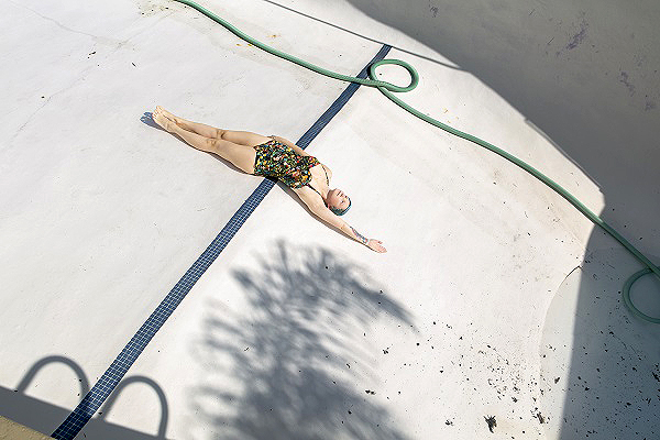 a photograph of a woman in a swimming suit lying on the bottom of a pool with no water in it by Natasha Rudenko