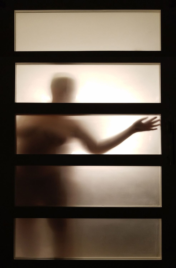 Photograph of a nude woman behind a paper screen in a hotel room by Kristine Schomaker